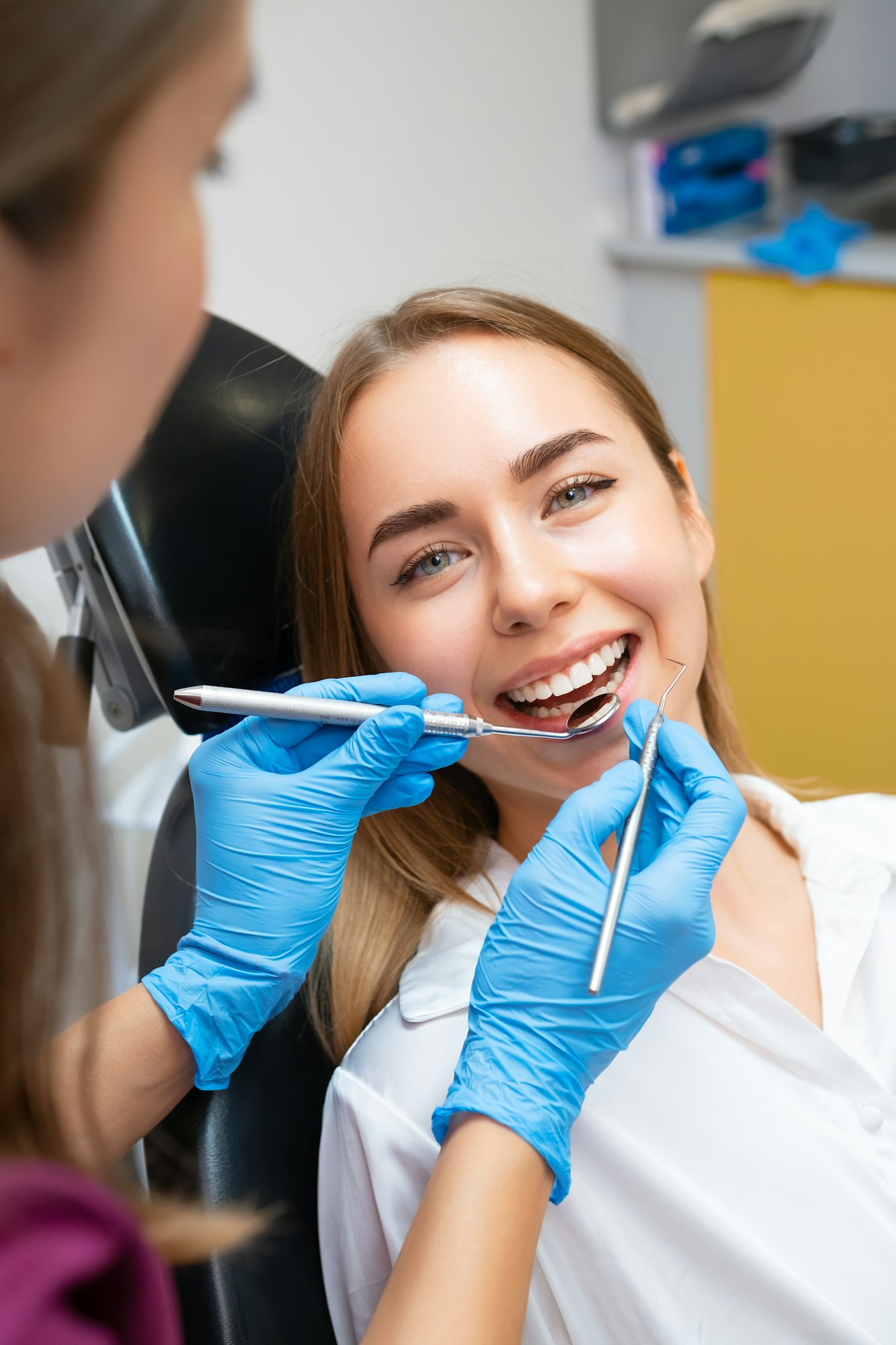 The dentist is performing dental treatment on a female patient with a flawless smile.